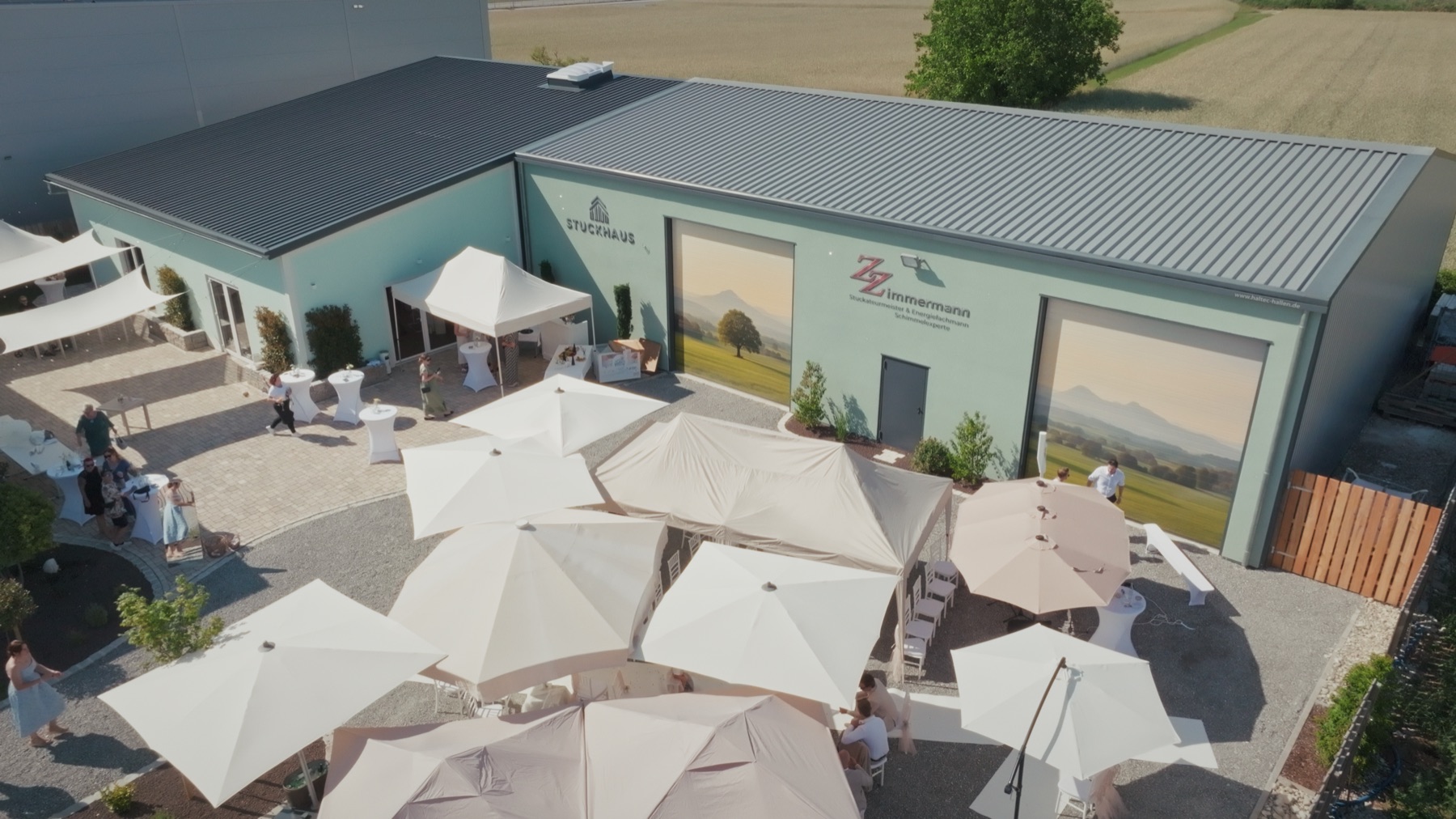 Der Hof des Stuckhauses mit Sonnenschirmen und Stehtischen vor der Halle